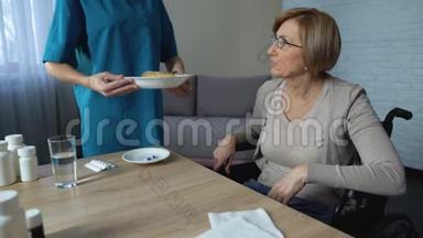 医护人员为坐轮椅的患病女士提供甜点盘